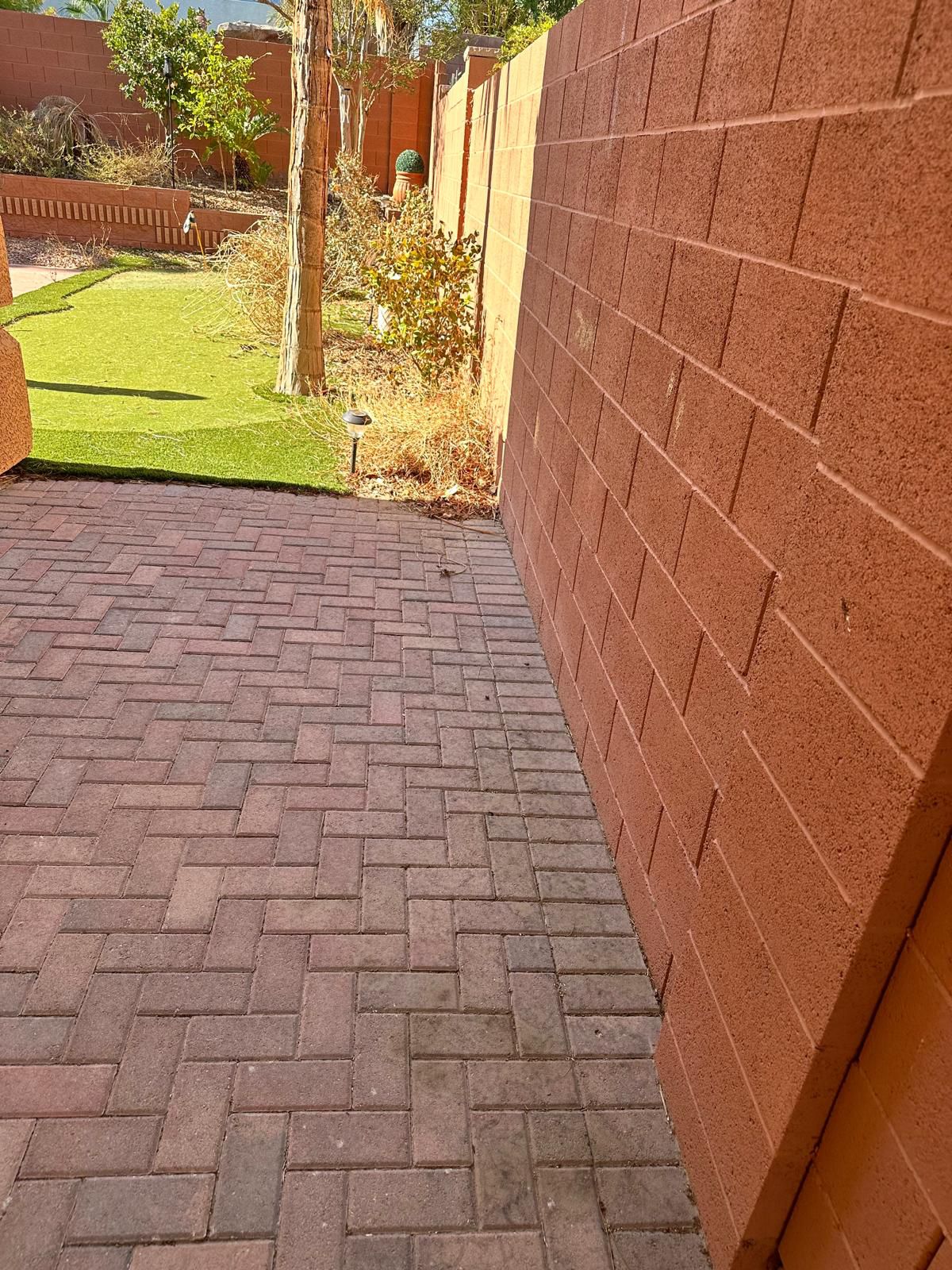 Brick paver walkway beside artificial turf lawn